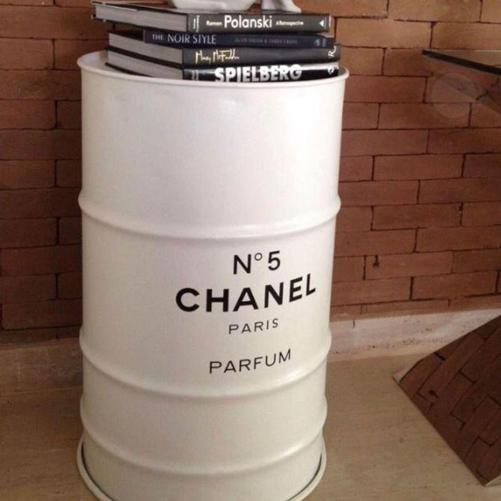 \u200bA white metal barrel with books on top, branded with Chanel No. 5.