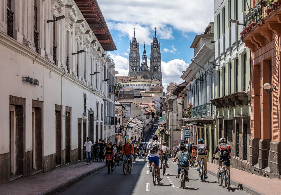 \u200bCyclists and pedestrians on a street in Quito facing the Basilica del Voto Nacional.