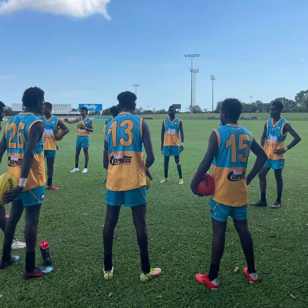 \u200bFootball players stand in a circle on a pitch.