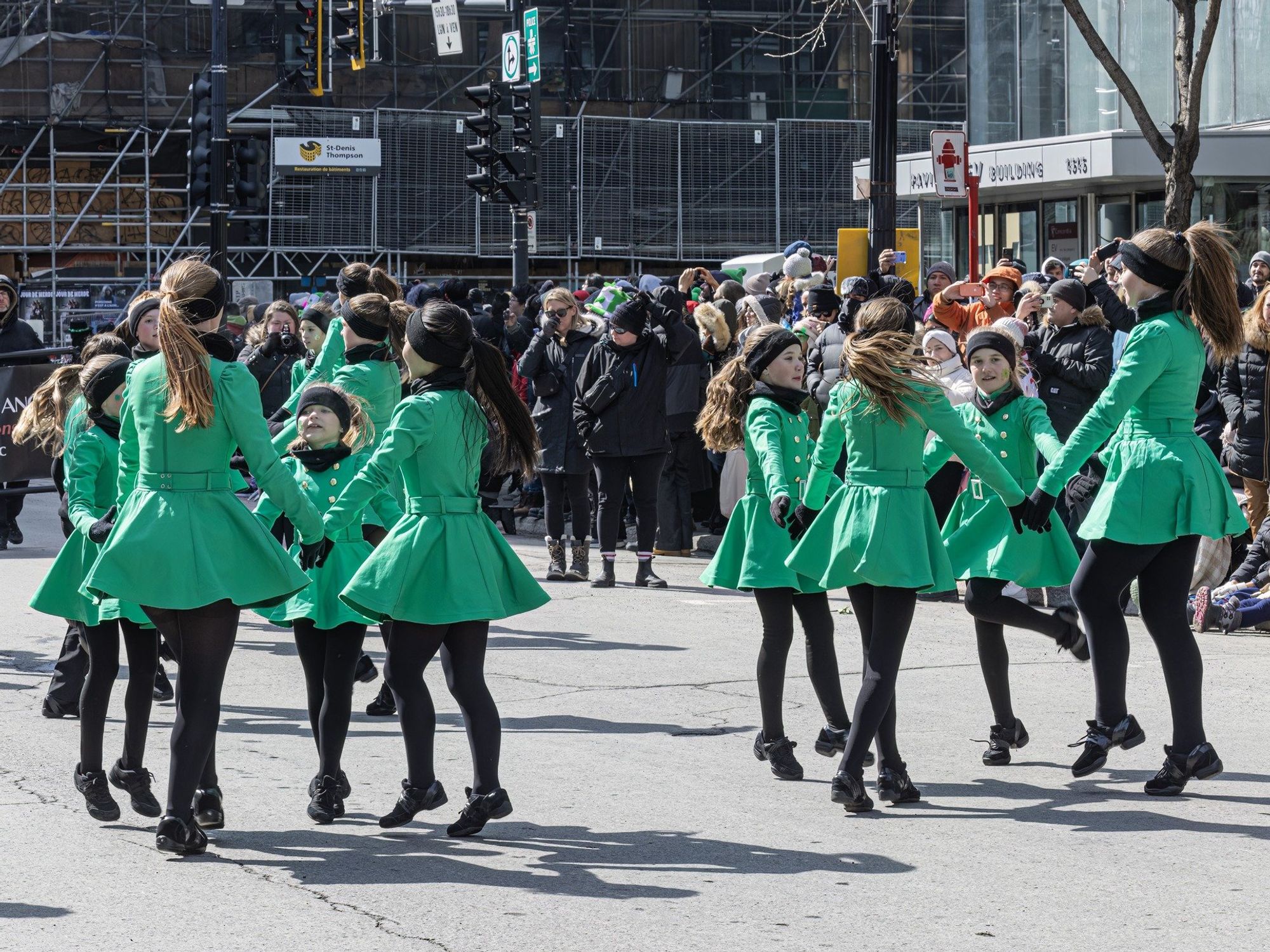 \u200bGirls in green coats dance in the street as part of the Saint Patrick's Day parade in Montreal.