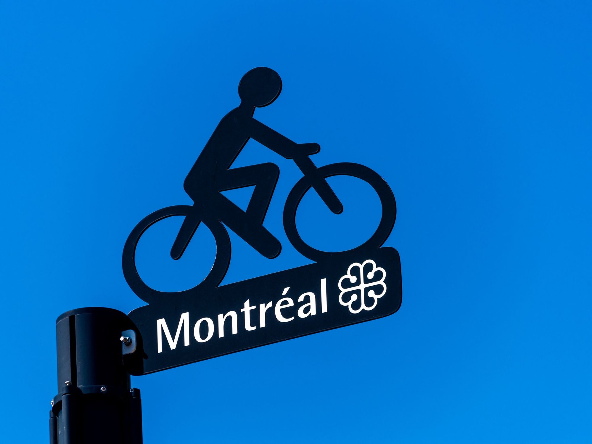 \u200bMontreal city logo below a metal bike silhouette over blue sky.