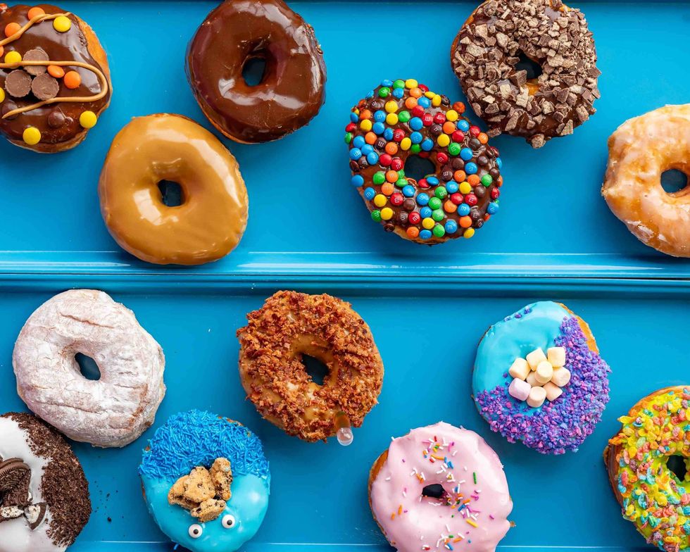 \u200bOver a dozen colourful donuts on a blue background.