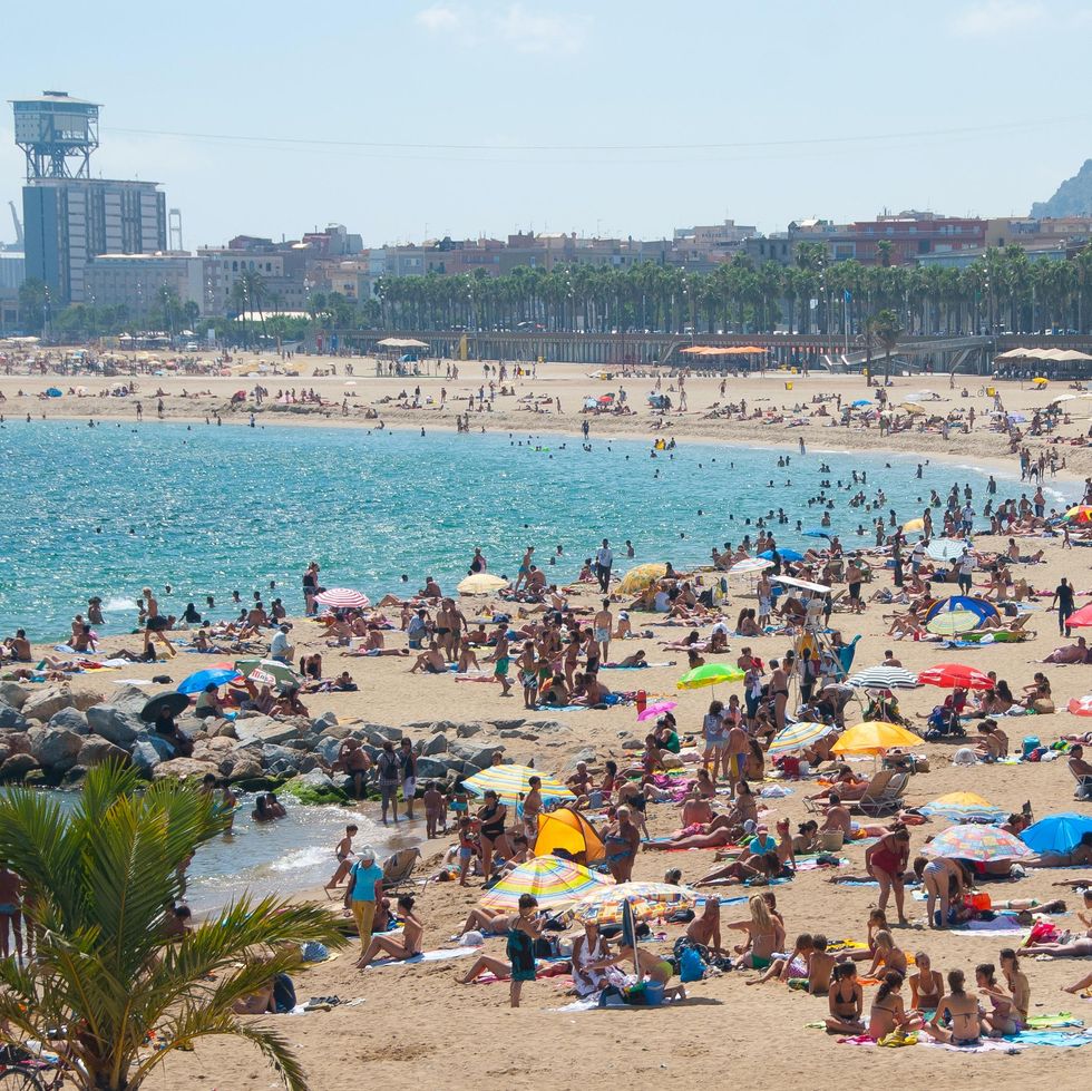 \u200bPeople on a beach in Barcelona.