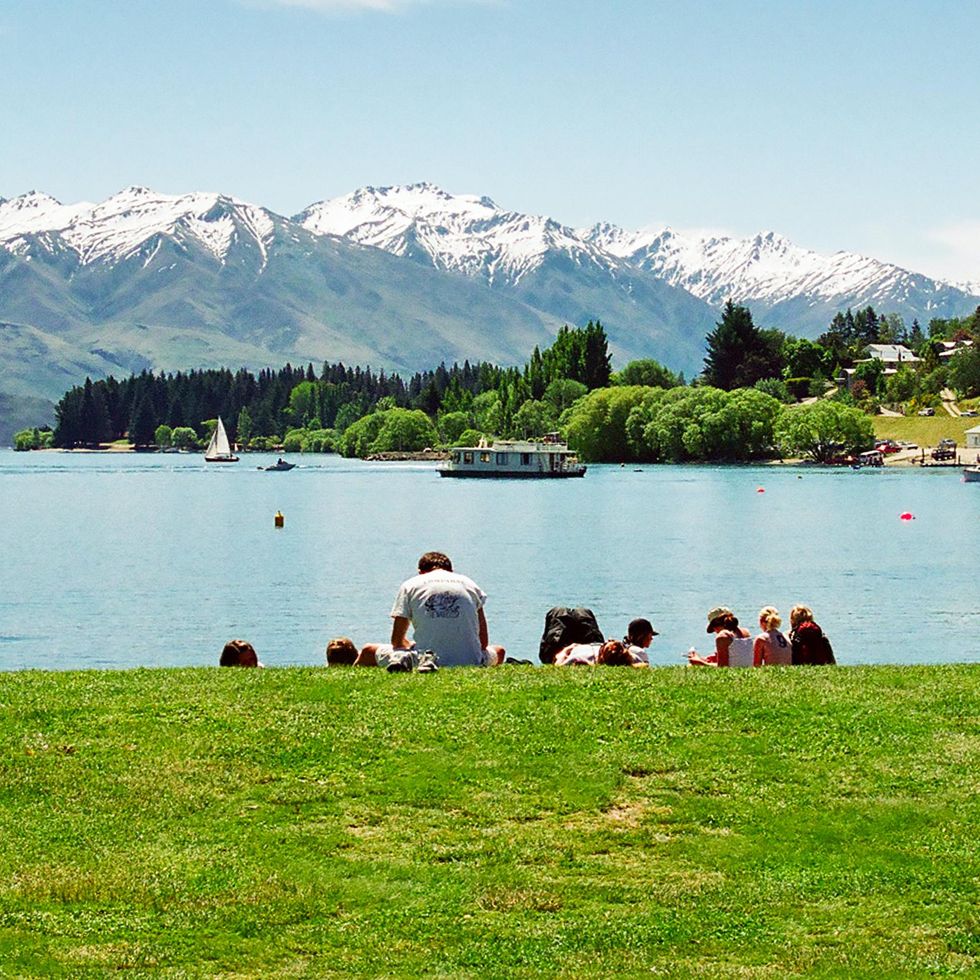\u200bPeople on the shore of lake Wanaka in the South Island of New Zealand.