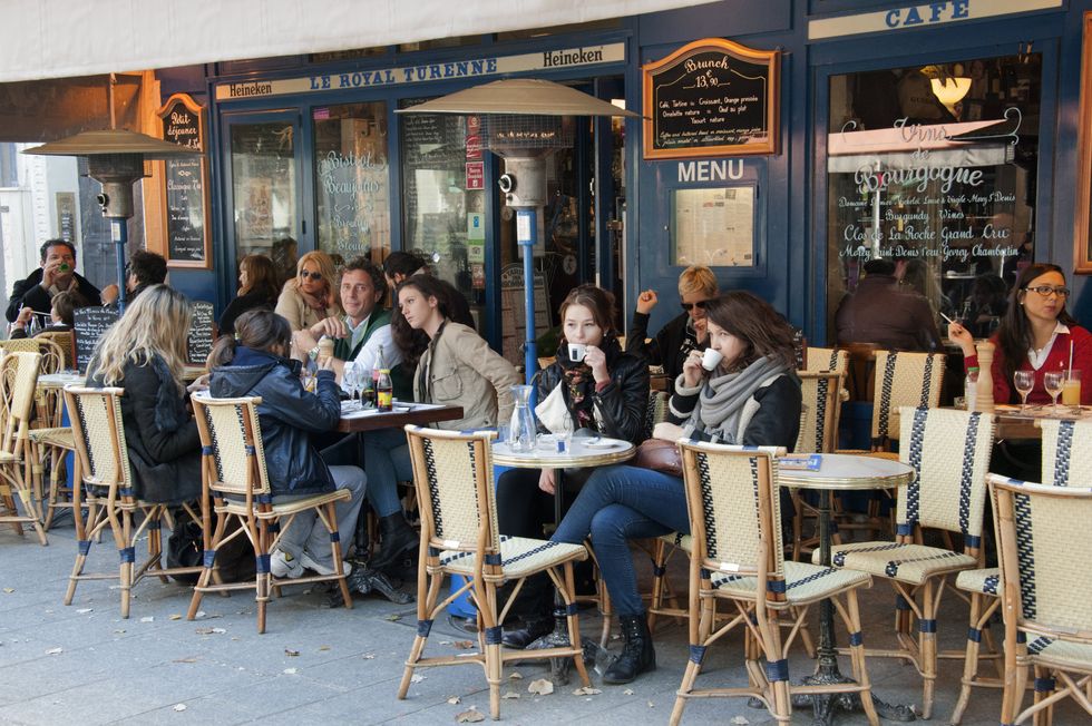 \u200bPeople sit outside a Parisian caf\u00e9.