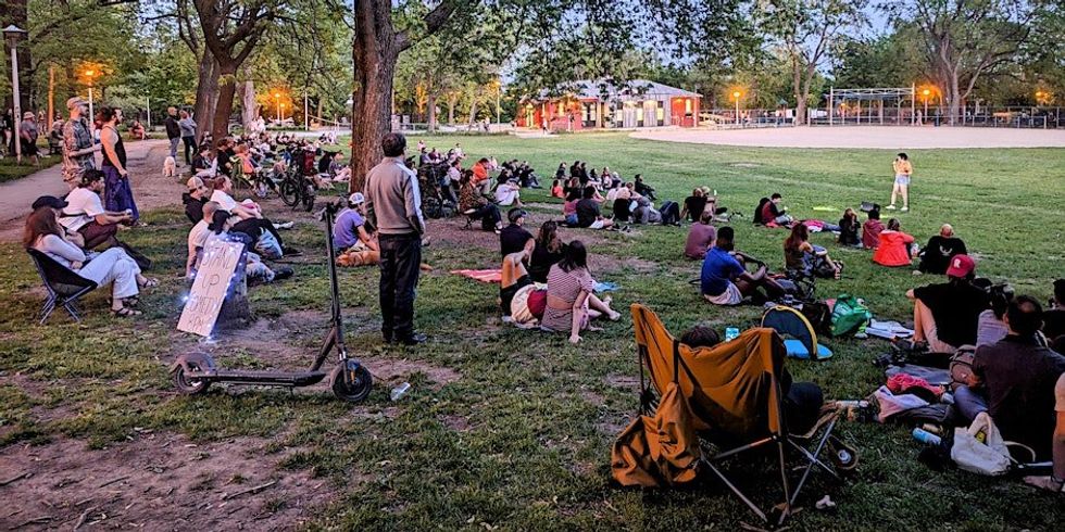 \u200bPeople watching a stand up comedy show in a park in Montreal.