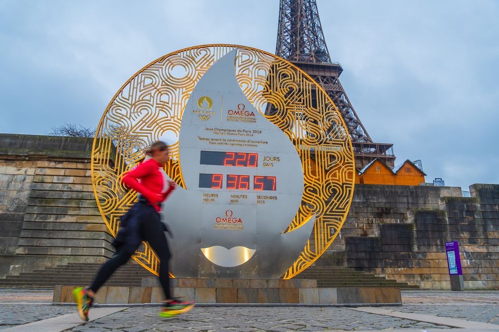 \u200bSomeone runs by the Paris Olympic countdown clock in front of the Eiffel Tower.