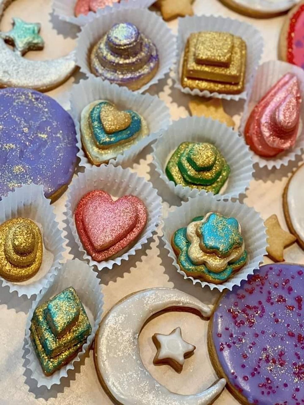 \u200bStacks of colourful, glittering sugar cookes in various shapes.