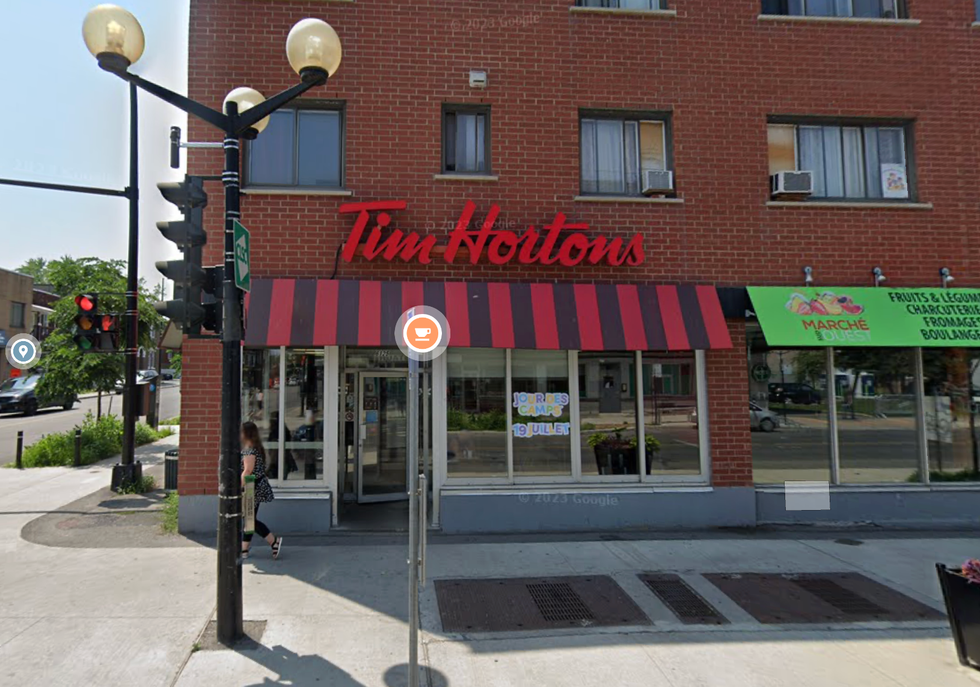 \u200bThe exterior of a Tim Hortons in Montreal during the summertime with restaurant logo placed above the entry.