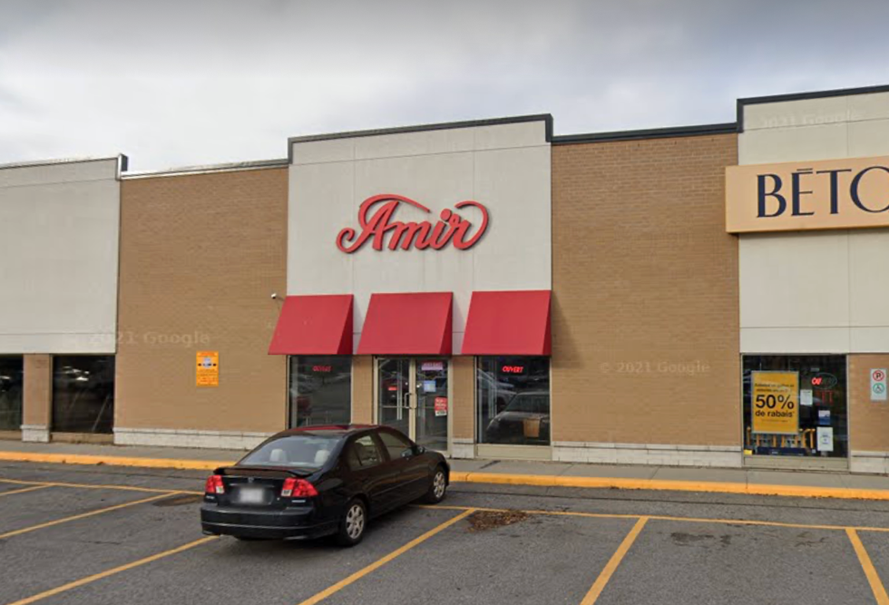\u200bThe exterior of an Amir restaurant in Montreal with a car parked out front.