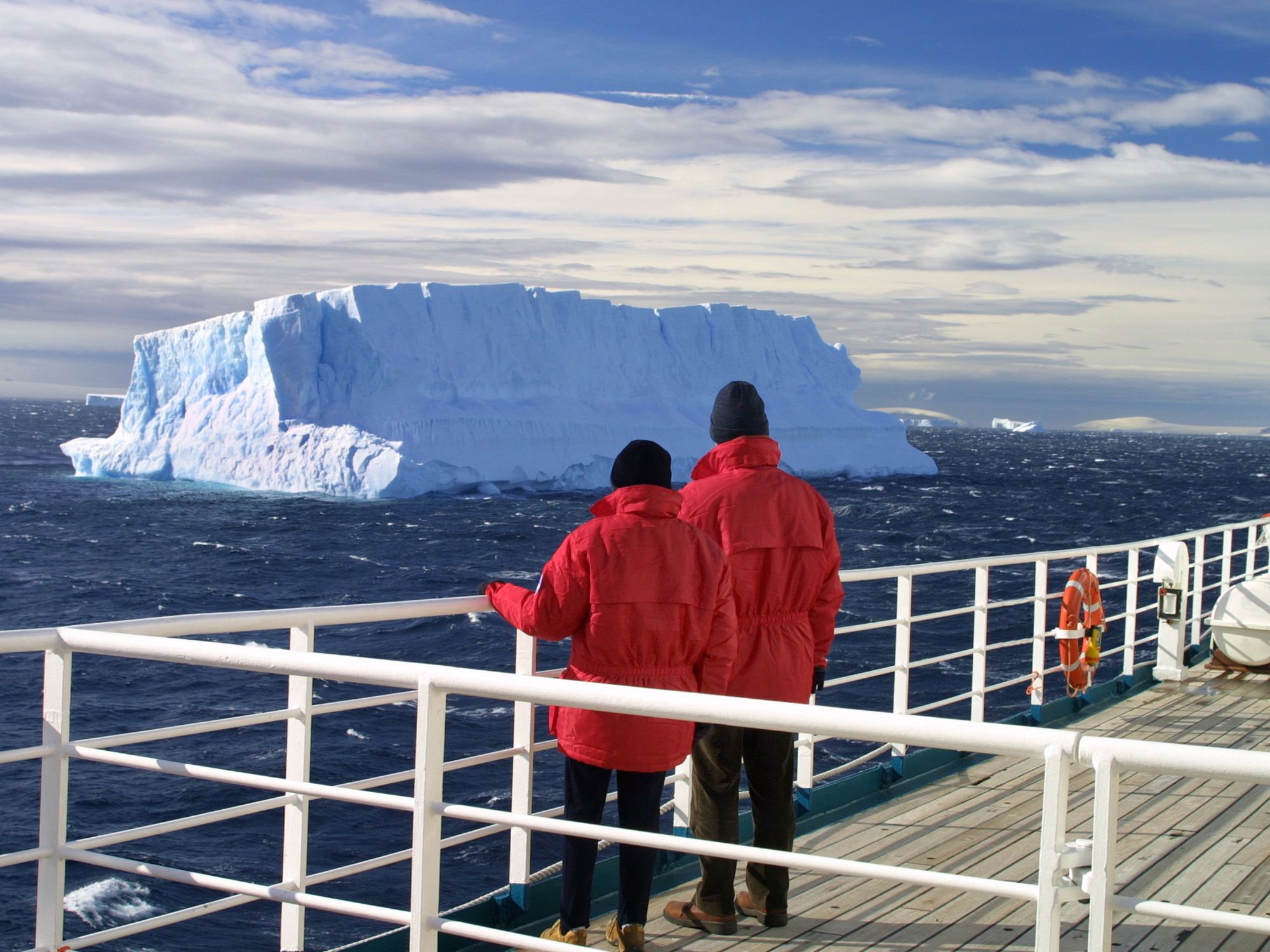 \u200bTwo passengers look at an iceberg from a cruise ship.