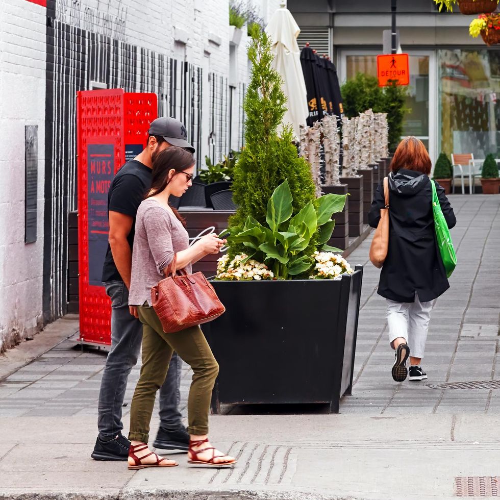 \u200bTwo people stare at a smart phone in Montreal.