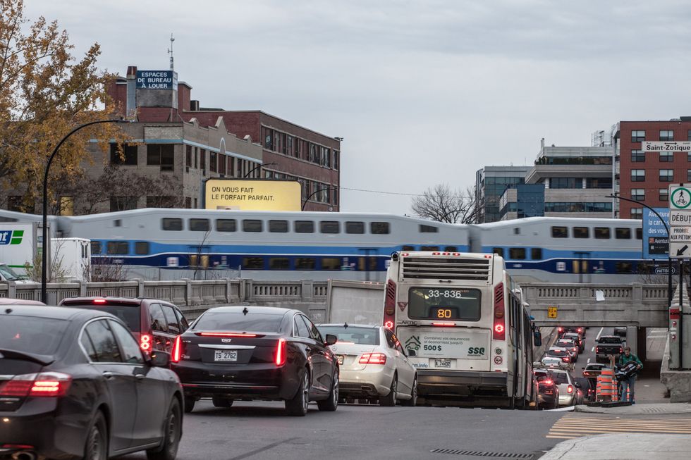 Vehicles backed up on av. du Parc in Montreal, while a train passes over a bridge.