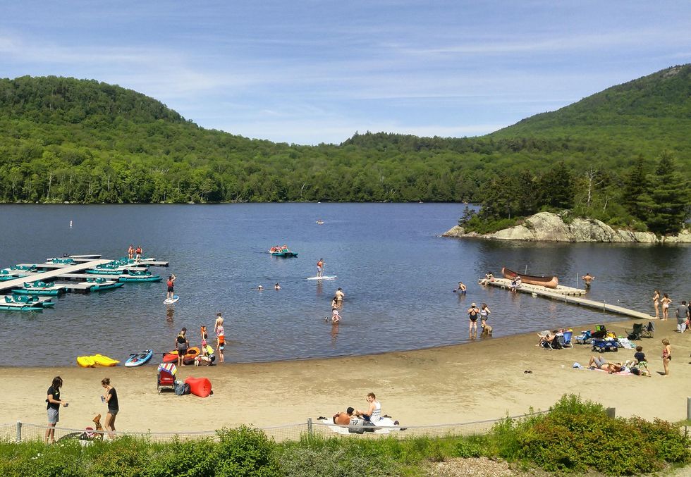 Visitors to Quebec's Parc national du Mont-Orford swim, boat, and lie on the beach on a summer day.