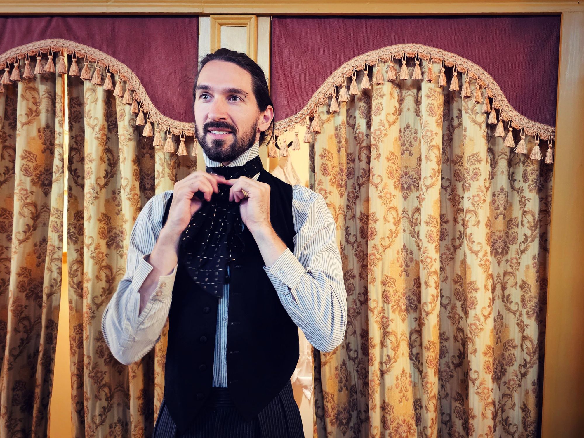 Will tying a cravate while wearing a high collar top and waistcoat.